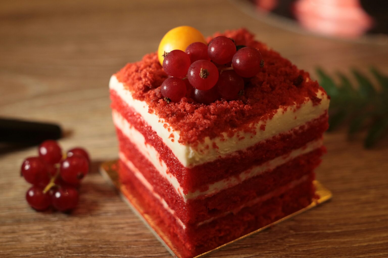 Delicious red velvet cake slice with cream cheese frosting and fresh berries on top.